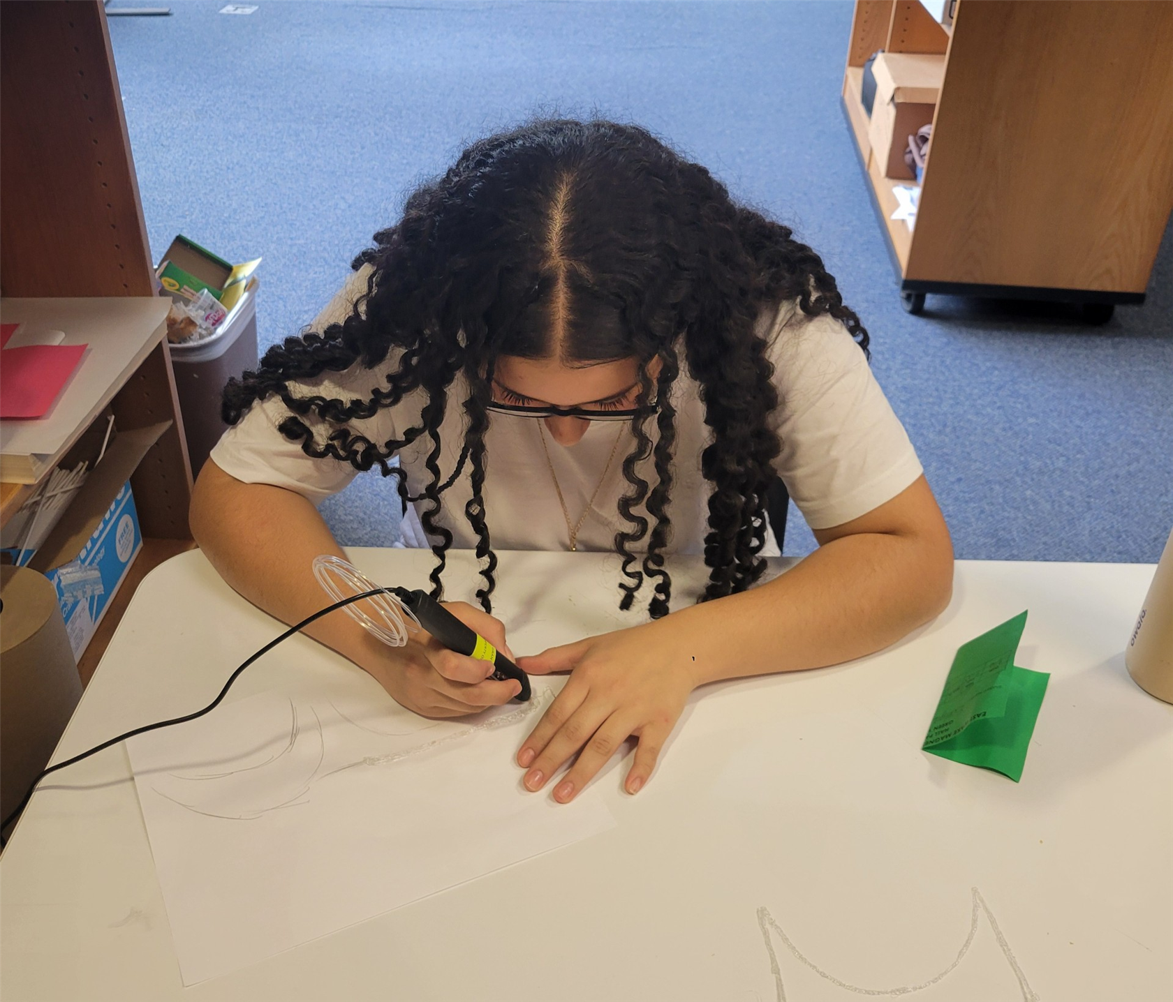 A student focuses on using a 3-D pen to create an object. 